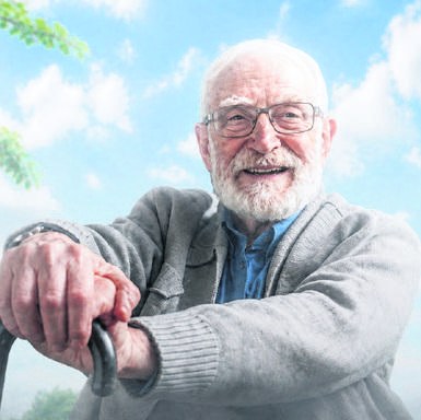 Lächelnder älterer Herr mit Gehstock vor blauem Himmel